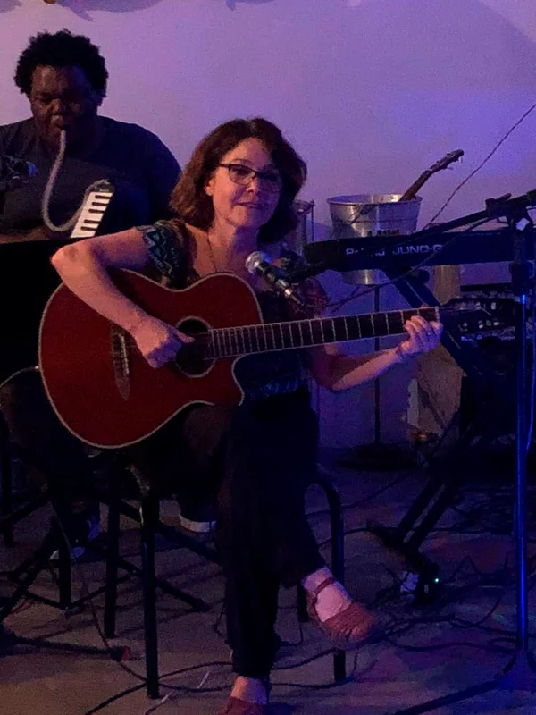 Dra. Beatriz Baldas tocando e cantando em apresentação musical